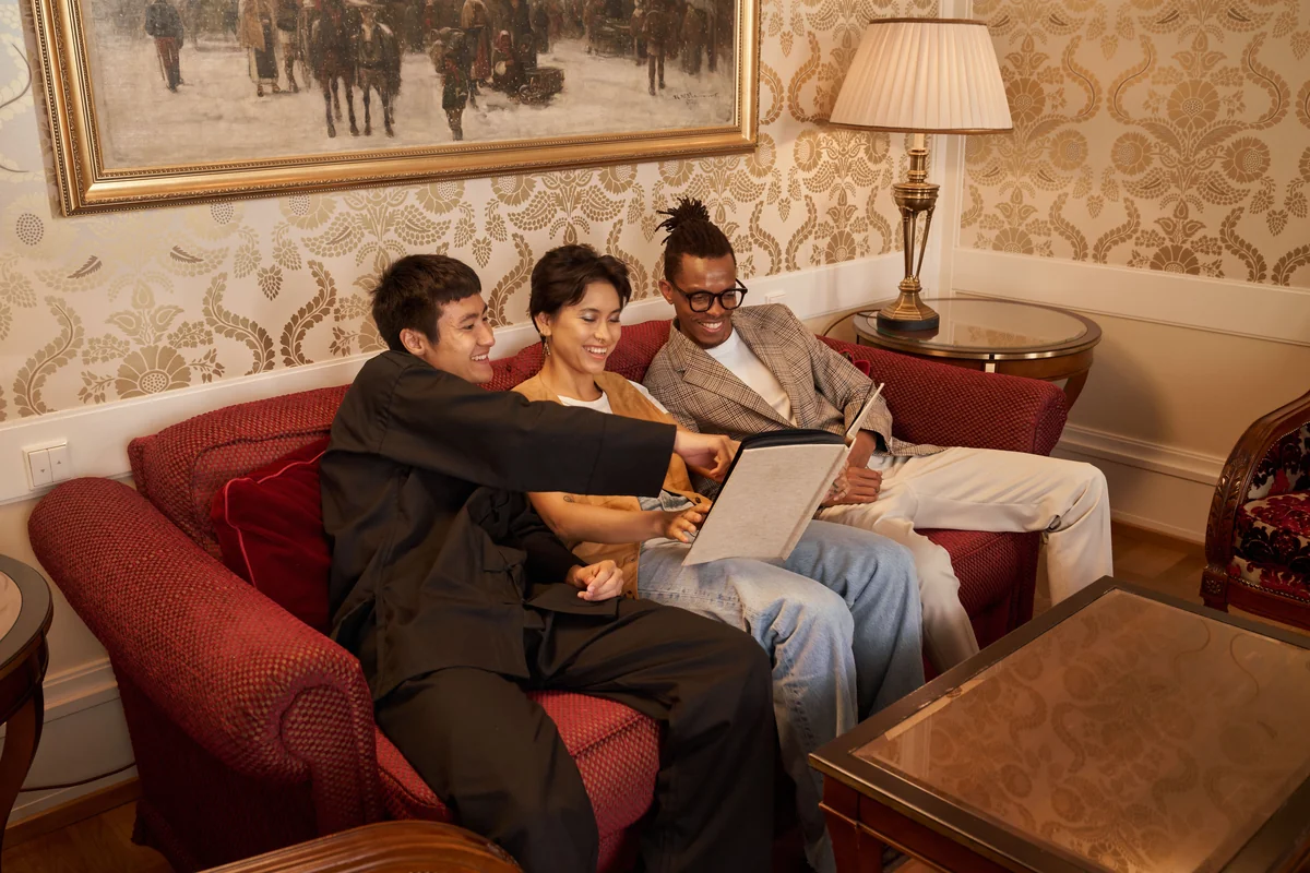 Three adults looking through an album together on a living-room sofa.
